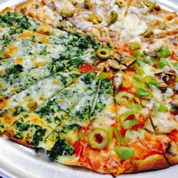 A large Brami's Kosher Pizza with four different toppings: spinach, olives, onions, and green peppers.