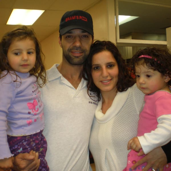 A family of four, two adults and two young children, posing for a photo indoors.