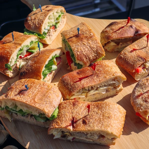 Assortment of fresh sandwiches with various fillings, cut in half and arranged on a wooden board.